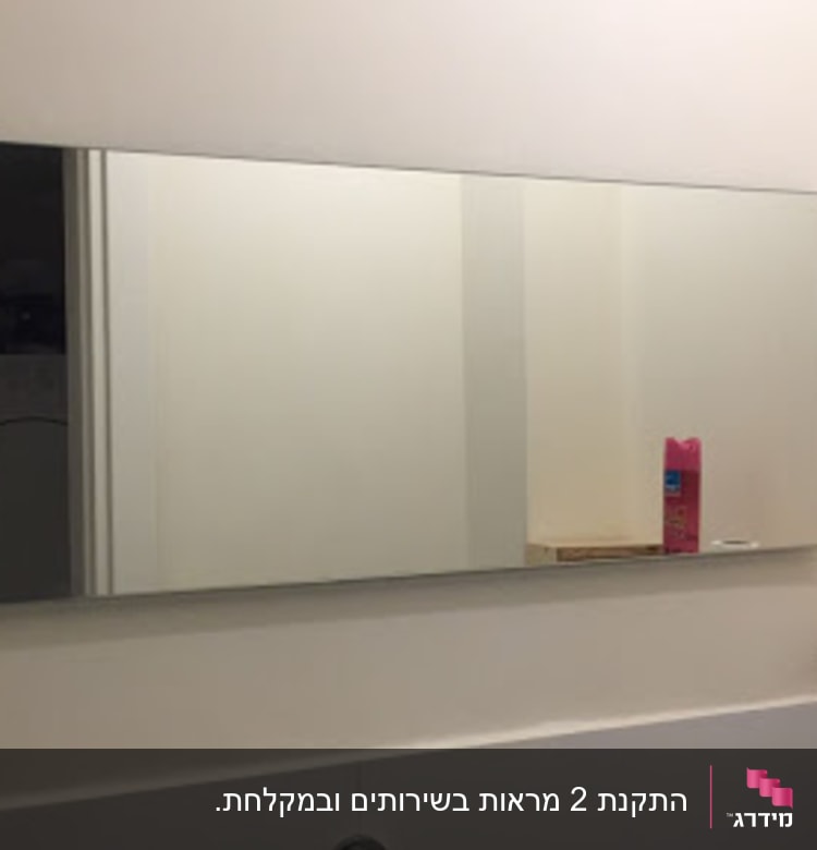 מראה מלבנית על קיר לבן בחדר אמבטיה